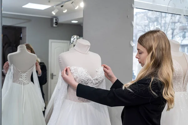 Beautiful young bride choosing perfect wedding dress in store for her best day. Concept of chosen the right dress.