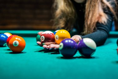 female hand collects colored balls after playing billiards and prepares a new game. Concept of spending free time with games