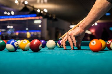 Siyah elbiseli güzel kadın ellerini elinde bir ıstaka tutarken ve bilardo katmanını deliğe sokmaya çalışırken görebilirsiniz. Bilardo sporu oyun konsepti