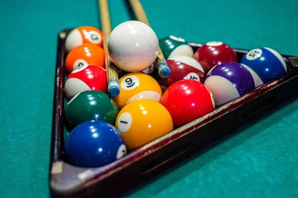 Billiard balls on the pool table with player's hands and stick. The concept of sports and gambling.