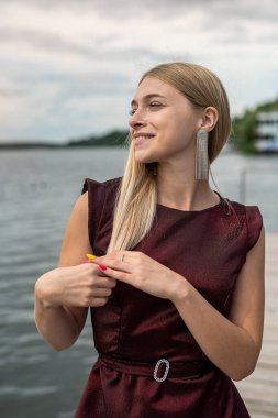 Gölde poz veren koyu kırmızı elbiseli güzel sarışın kız, romantik.