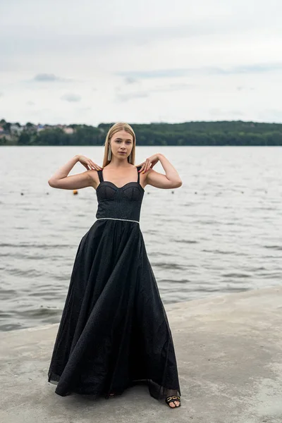 空と水 自由を背景に長い暗いドレスで美しい若い女性 — ストック写真