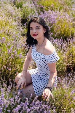 Lavanta tarlasında poz veren kırmızı rujlu güzel esmer kadın.