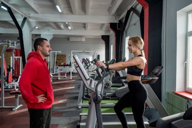 Sportif, güzel bir bayan antrenör ve spor salonunda spor giyim bölümünde pompalanmış bir erkek antrenör. Spor salonundaki genç koçlar kavramı