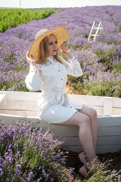 beautiful young girl in a straw hat sitting on a background of lavender field