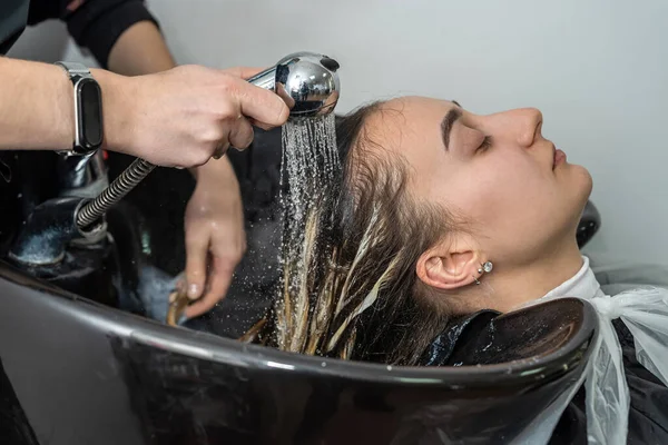 in an elite hairdresser\'s beautiful young woman washes her head in a special chair. The concept of washing the head in a beauty salon
