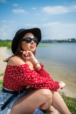 Güzel bir kadın göl kenarında oturuyor, yaz günü. Yaşam tarzı rahatla