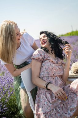 Happy sisters looking at lavender flowers in big field