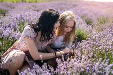 Happy sisters looking at lavender flowers in big field