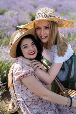 Happy sisters looking at lavender flowers in big field