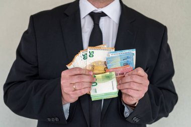 Takım elbiseli bir iş adamı iş yerinde euro banknotlarını sayar. Üretimde ücret kavramı