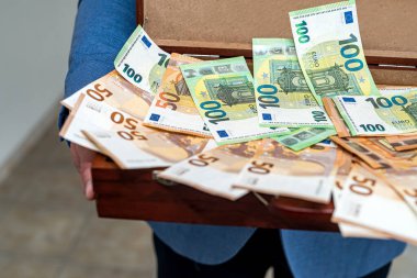 Klasik takım elbiseli bir adam, anlaşma için yüklü miktarda paranın olduğu açık bir davayla ayakta duruyor. Pazarlık için büyük miktarda para konsepti