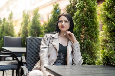 Boş bir masada oturmuş kahvesini bekleyen şık genç bir kadın, dinleniyor.