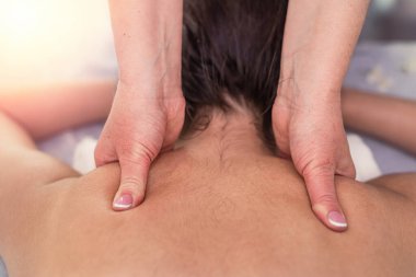 young woman receive manual relax massage  on neck lying on table in spa salon. therapeutic massage procedure.