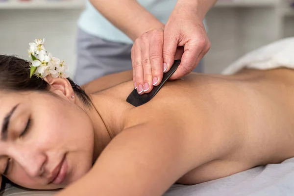 spa therapist make relax massage with a gouache scraper in salon, wellness