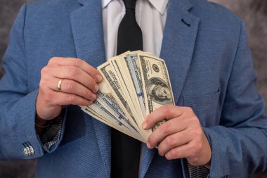 a university lecturer in a suit takes bribes in dollars and hides money in his pocket. The concept of large bribes in educational institutions
