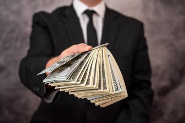 Tecrübeli bir işadamı en iyi markalarla giyinmiş bu işe büyük miktarda yatırım yapmak istiyor. Dolarları olan takım elbiseli bir adam.