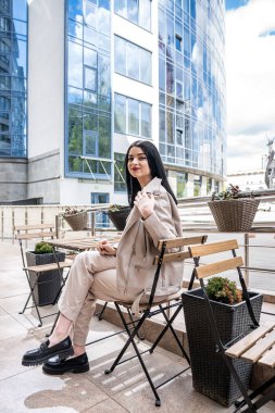 business lady waiting for her partner sitting at a table in front of a modern business center