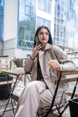 business lady waiting for her partner sitting at a table in front of a modern business center