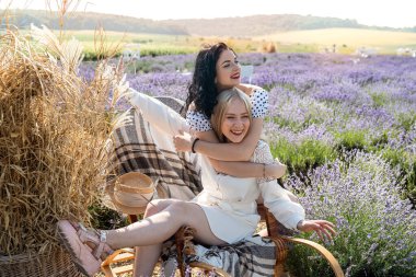 Two happy young women posing on lavender field at sunset