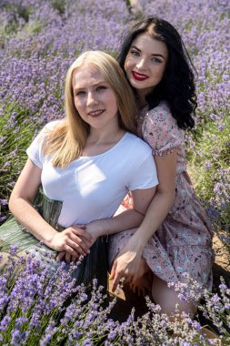 Happy sisters looking at lavender flowers in big field