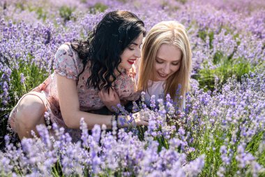 Happy sisters looking at lavender flowers in big field