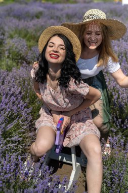Happy sisters looking at lavender flowers in big field