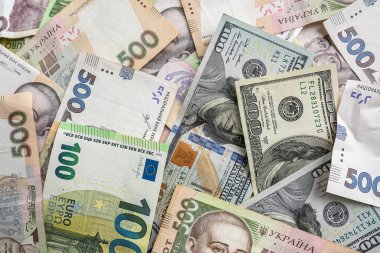 many euro and hryvnia banknotes lie on the table next to a wallet with money and a calculator on the table. Currency concept