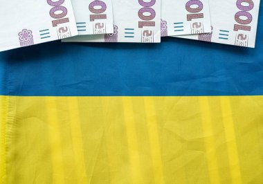 Stack of Ukrainian hryvnia banknotes on the background of the Ukrainian flag. The concept of the Ukrainian currency