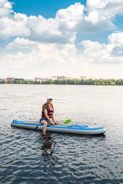 an experienced athlete in a vest rides on the water on a board sap on the lake in sunny beautiful weather. The concept of a healthy lifestyle