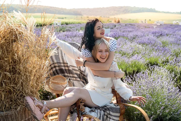 Two happy young women posing on lavender field at sunset