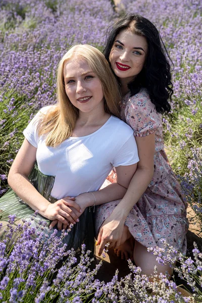 Happy sisters looking at lavender flowers in big field