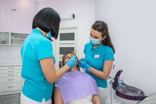 Μια Γυναίκα Οδοντίατρος Και Βοηθός Της Ειδικά Ρούχα Εξετάζουν Δόντια — Φωτογραφία Αρχείου