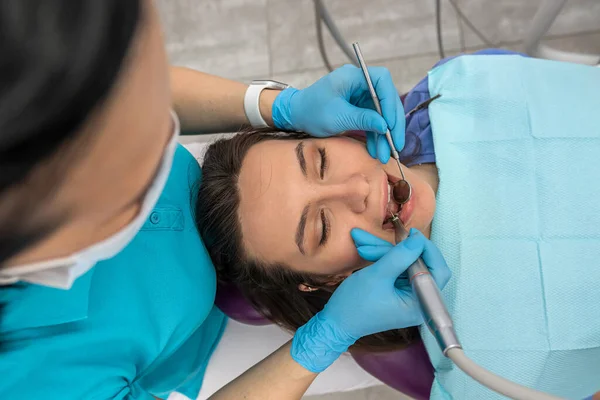top view of female patient teeth whose teeth looks at dentist woman. Female dentist treats her patient