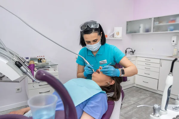 professional woman dentist performs a professional examination of the oral cavity in a beautiful woman. Health concept