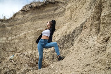 Sıska, genç ve güzel bir kadın yaz mevsiminde çölün arka planında doğada rahatlar.