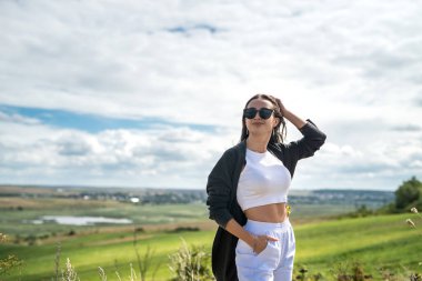 Güzel kız, uzun çimenli bir çayırda güneşli bir yaz gününün tadını çıkarıyor. Yaşam biçimi