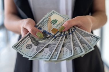 Genç iş kadını, elinde dolarla ofiste duruyor. maaş ir rüşvet konsepti