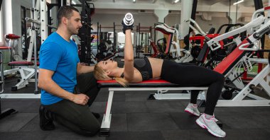 A handsome young trainer with a good figure trains a young client who came to the gym. The concept of overweight