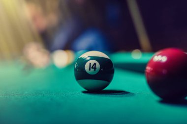 Siyah elbiseli güzel kadın ellerini elinde bir ıstaka tutarken ve bilardo katmanını deliğe sokmaya çalışırken görebilirsiniz. Bilardo sporu oyun konsepti