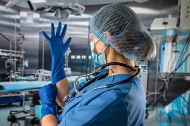 Bayan doktor ya da mavi ceketli hemşire kauçuk mavi eldivenler giyip hastayı ameliyathanede muayene etmeye hazırlanıyor.