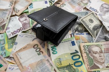 many euro and hryvnia banknotes lie on the table next to a wallet with money and a calculator on the table. Currency concept