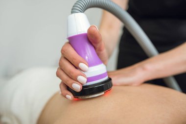 masseur use hardware anti-cellulite massage her female client as anticellulite procedure for loss weight