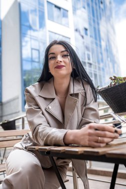business lady waiting for her partner sitting at a table in front of a modern business center