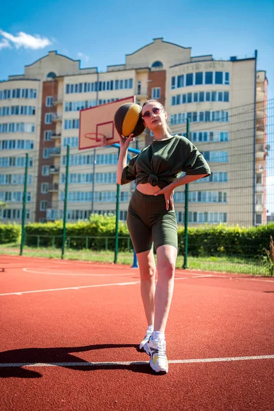 in tight-fitting sports uniform, a woman is playing basketball in an open-air stadium. Healthy lifestyle sports game sports concept