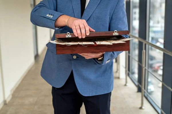 young boss businessman in expensive suit with tie holds suitcase with euro banknotes. The concept of the euro in a suitcase for a man with the tax