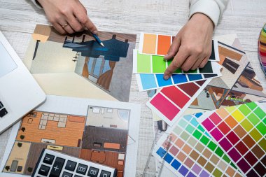 male architect designer in the office selects a palette of colors for drawings of the house on the project. Man's hands on the table with color palettes. Choice of colors from the palette