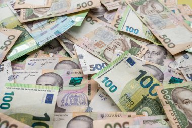 Top view of various euro and Ukrainian hryvnia banknotes on a spacious table. The concept of different currencies