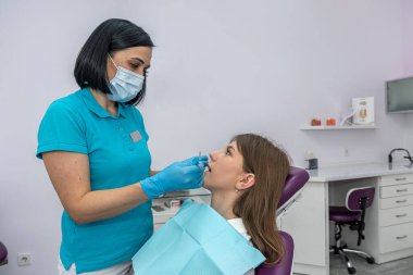 young girl lying in a woman's dentist chair on a dental examination. Teeth examination concept