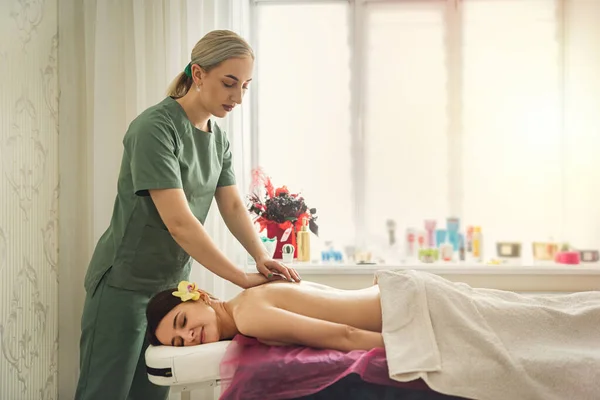 female therapist specialist makes anti-cellulite massage on back woman client at spa salon. health and beauty concept